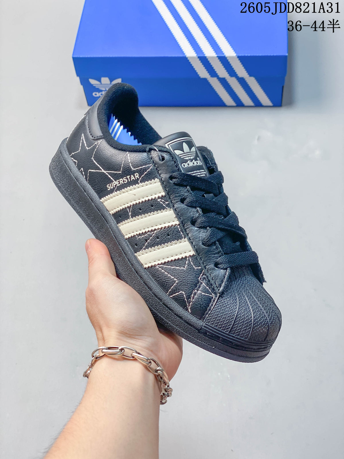 Close-up of a dark Adidas Superstar with light stripes, star graphics and a shell-shaped toe.