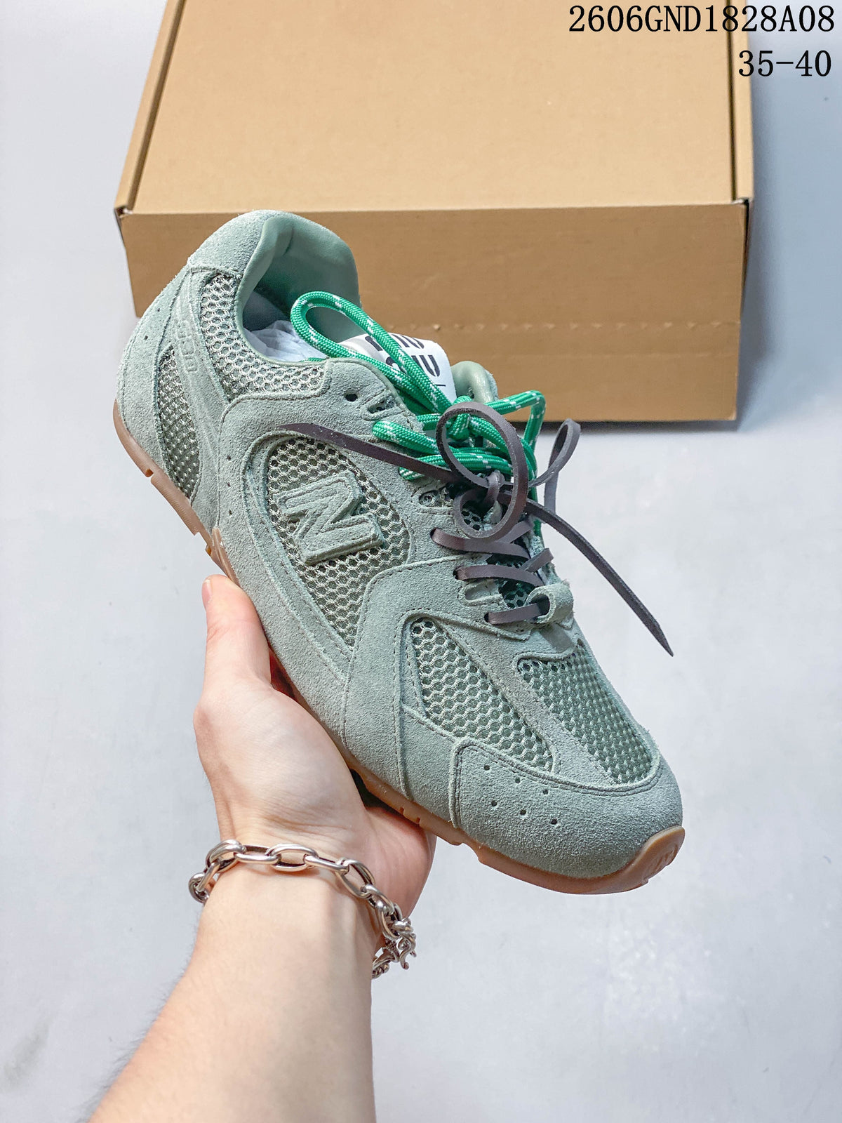 Close view of a muted green sneaker showing mesh panels, textured overlays and side branding.