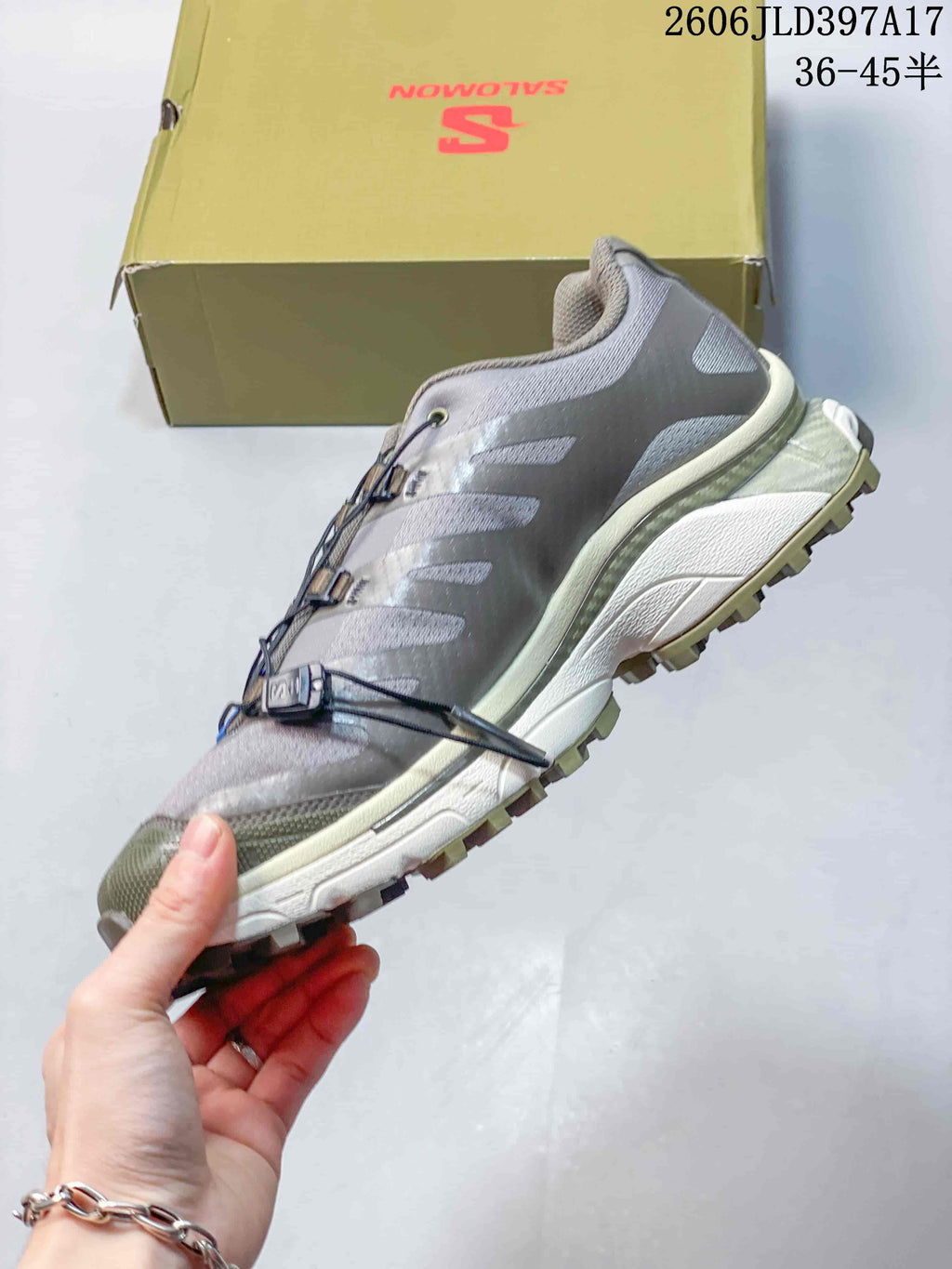 Side view of the gray shoe with layered panels and a lugged outsole.