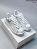 Pair of white low-top lace-up sneakers with gray heel panels and thick white soles