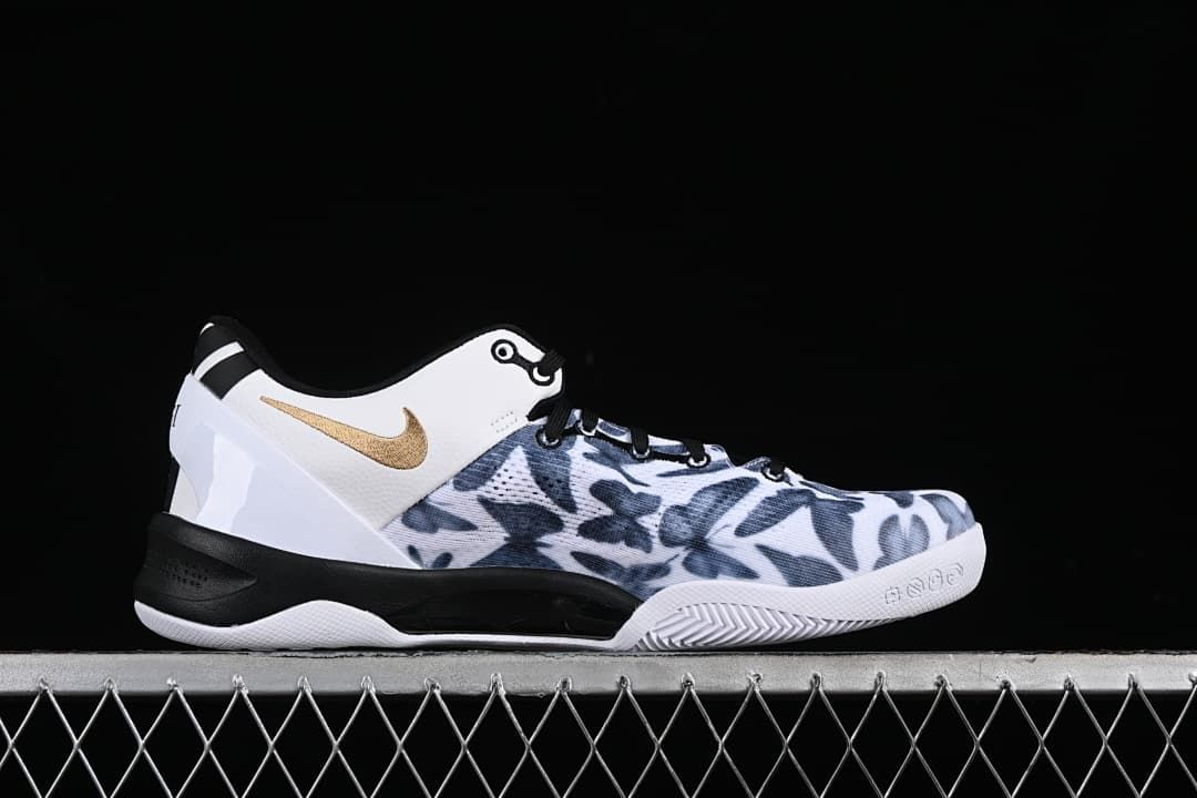 Side profile of the shoe with a white heel panel, gold swoosh, patterned upper, and black midsole.