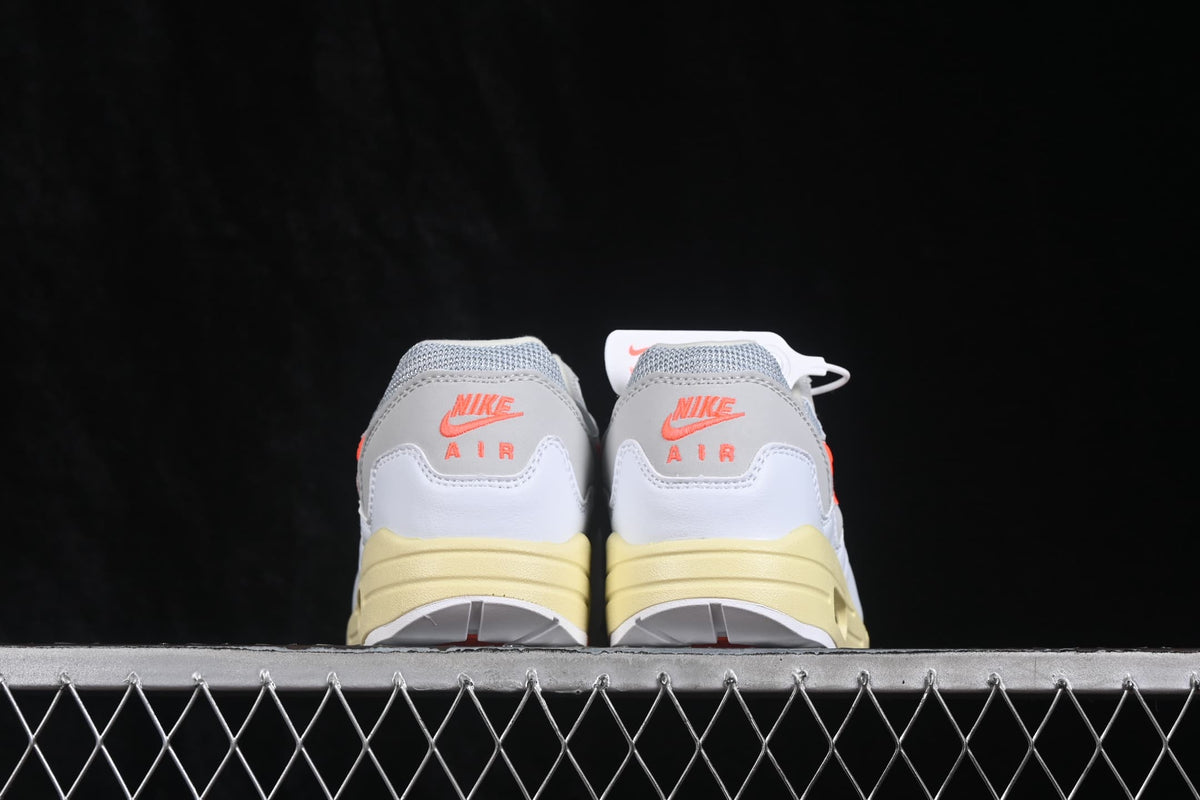 Rear view showing orange Nike Air branding on the white heel panels and cream-colored midsoles.