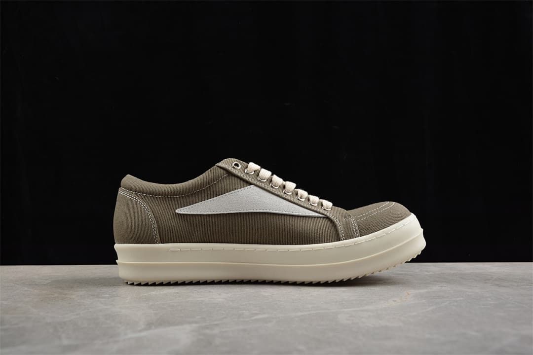 Side profile of a brown canvas low-top sneaker with a light-colored side detail and ridged sole