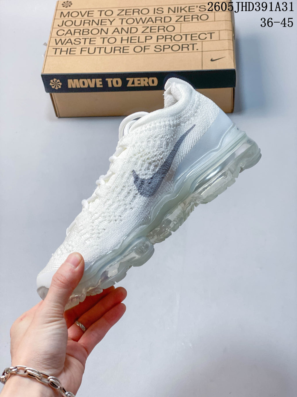 Side view of the white knit shoe with gray Swoosh and translucent sole.