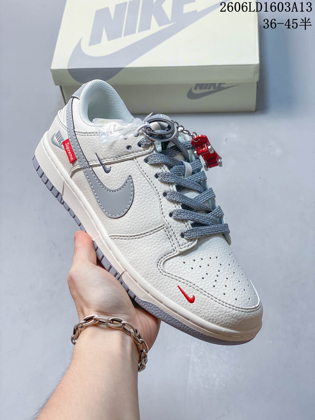 Angled side view showing grey Swoosh, red details, and lace accessories