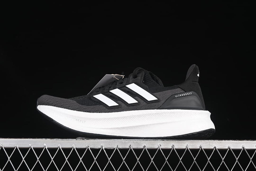 Side view of a black Adidas Ultraboost 5 shoe with white stripes and a white midsole
