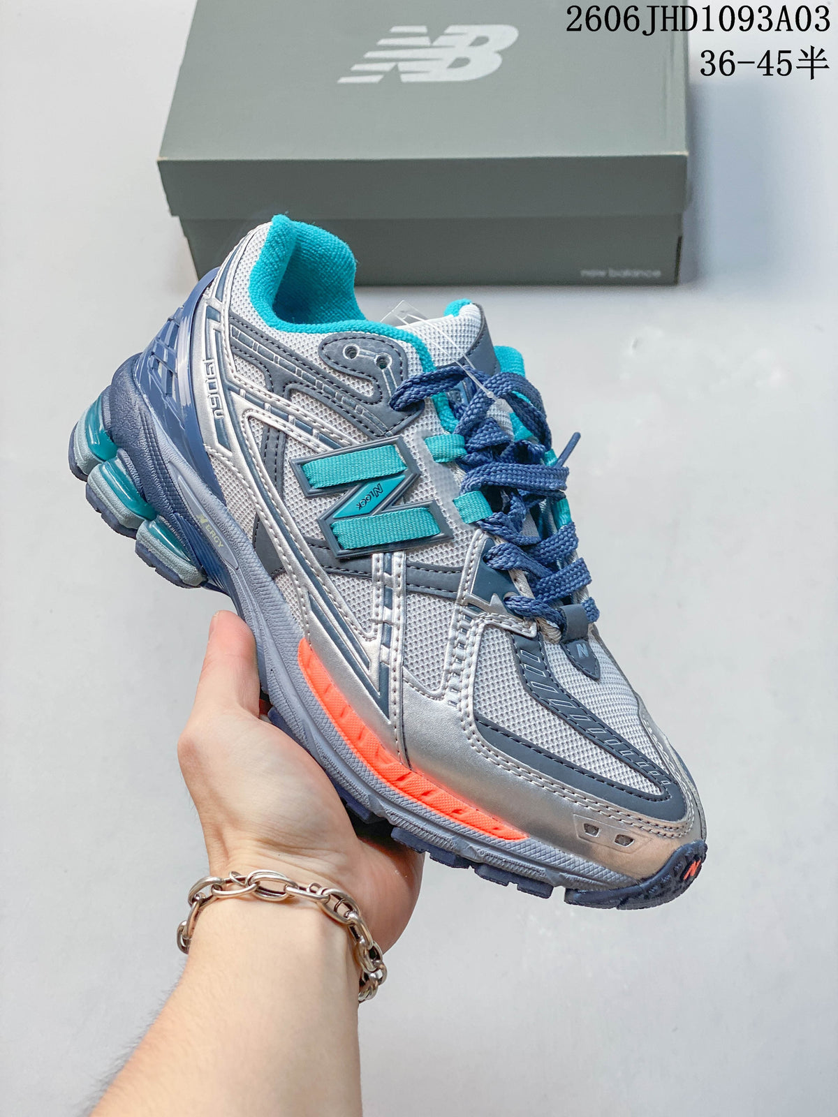 Silver and gray New Balance 1906U sneaker with blue and orange accents