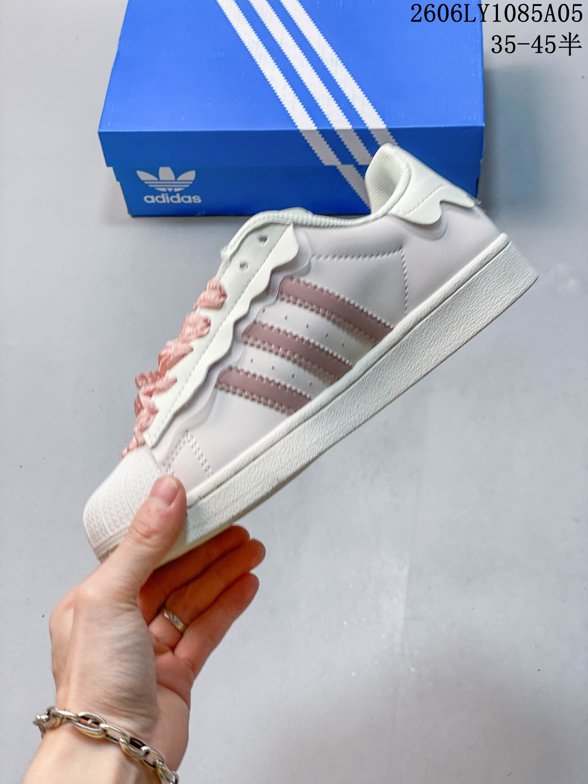 Side profile of the off-white Superstar sneaker with pale pink stripes and a textured sole.