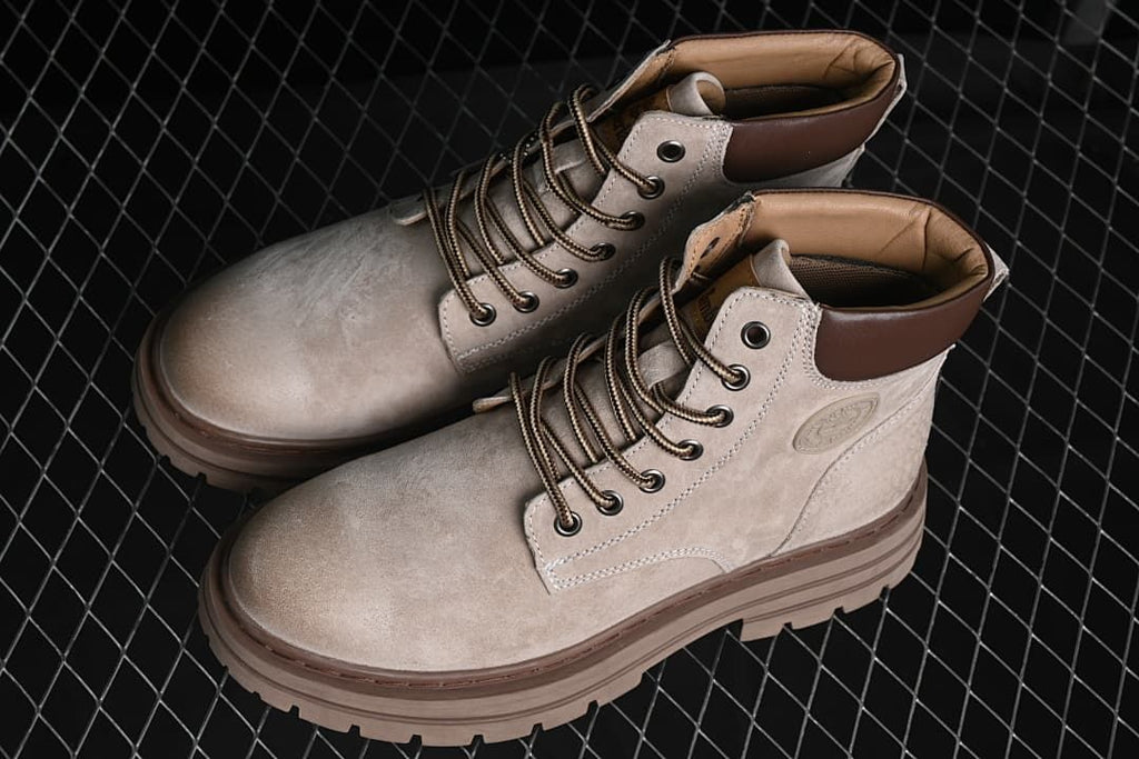 Pair of sand-colored high-top boots with brown collars and lugged soles