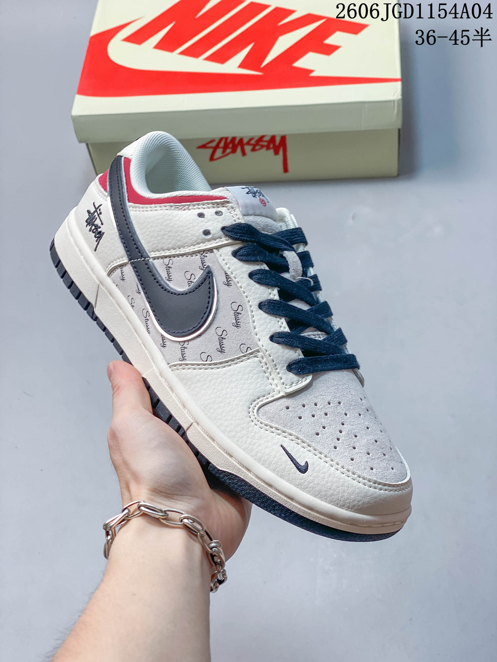 Angled side view of a Nike SB Dunk Low sneaker with navy and red accents and repeating script graphics.
