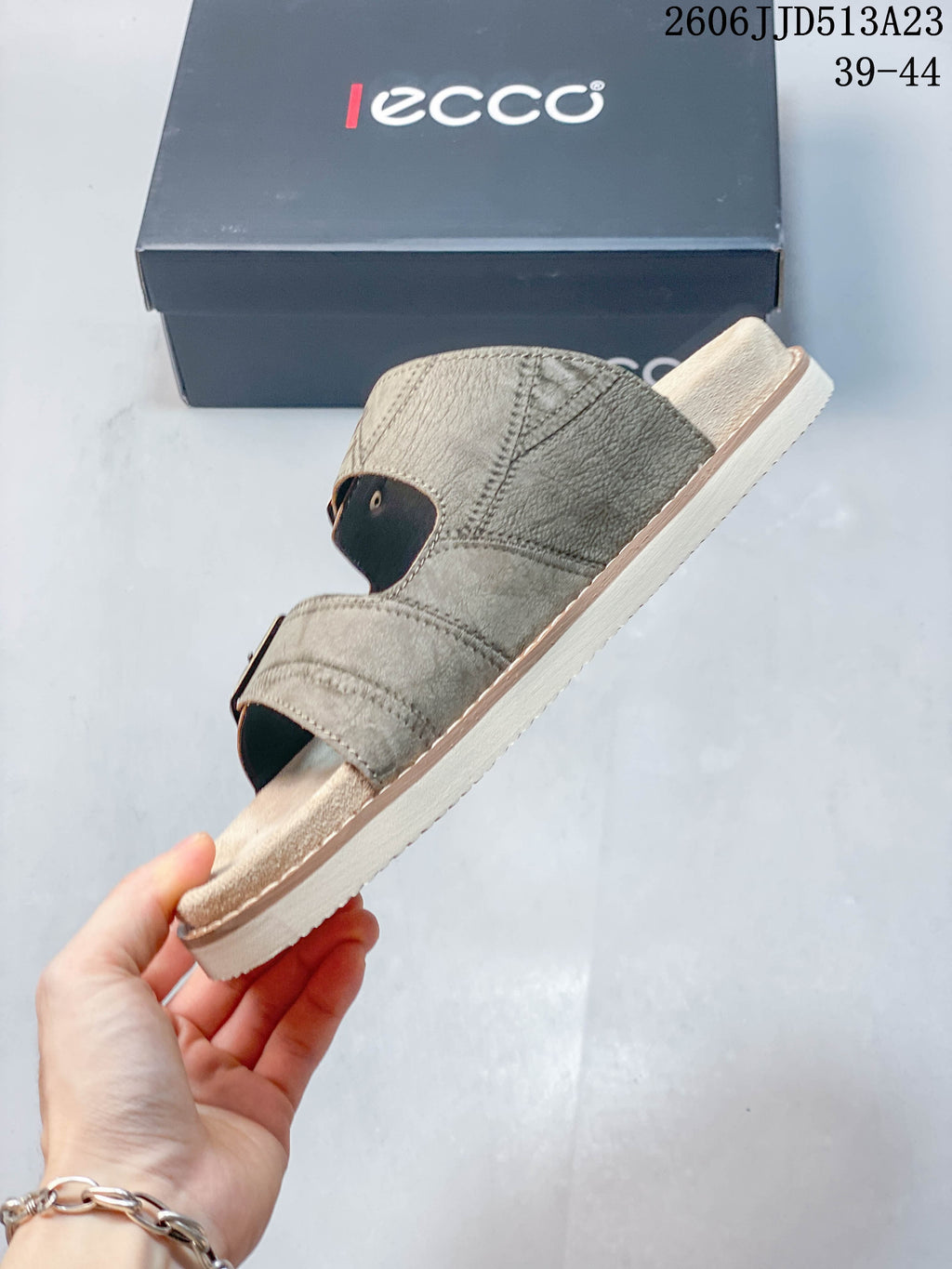 Side profile of a taupe slide sandal with two buckle straps.
