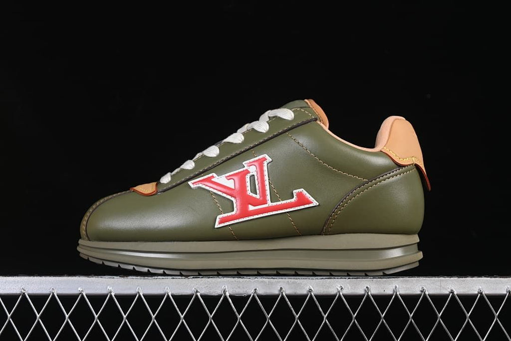Side view of an olive green low-top sneaker with tan accents, cream laces, and a red-and-white LV-style emblem
