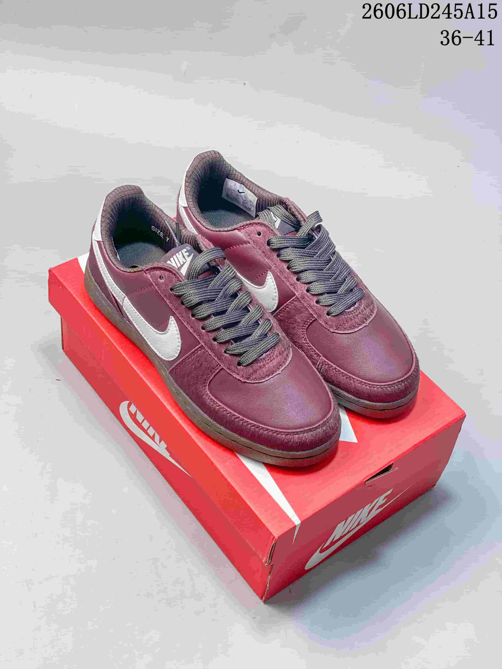 Pair of burgundy Nike Field General 82 low-top sneakers with light-colored side panels and dark laces, displayed on a red shoe box.