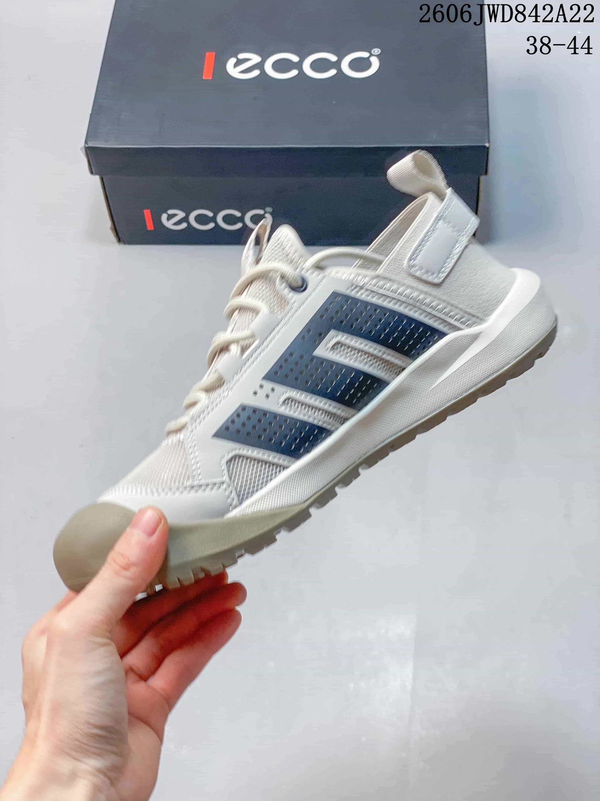 Side profile of a light grey sneaker with dark panels, lace-up fastening and a rugged outsole.