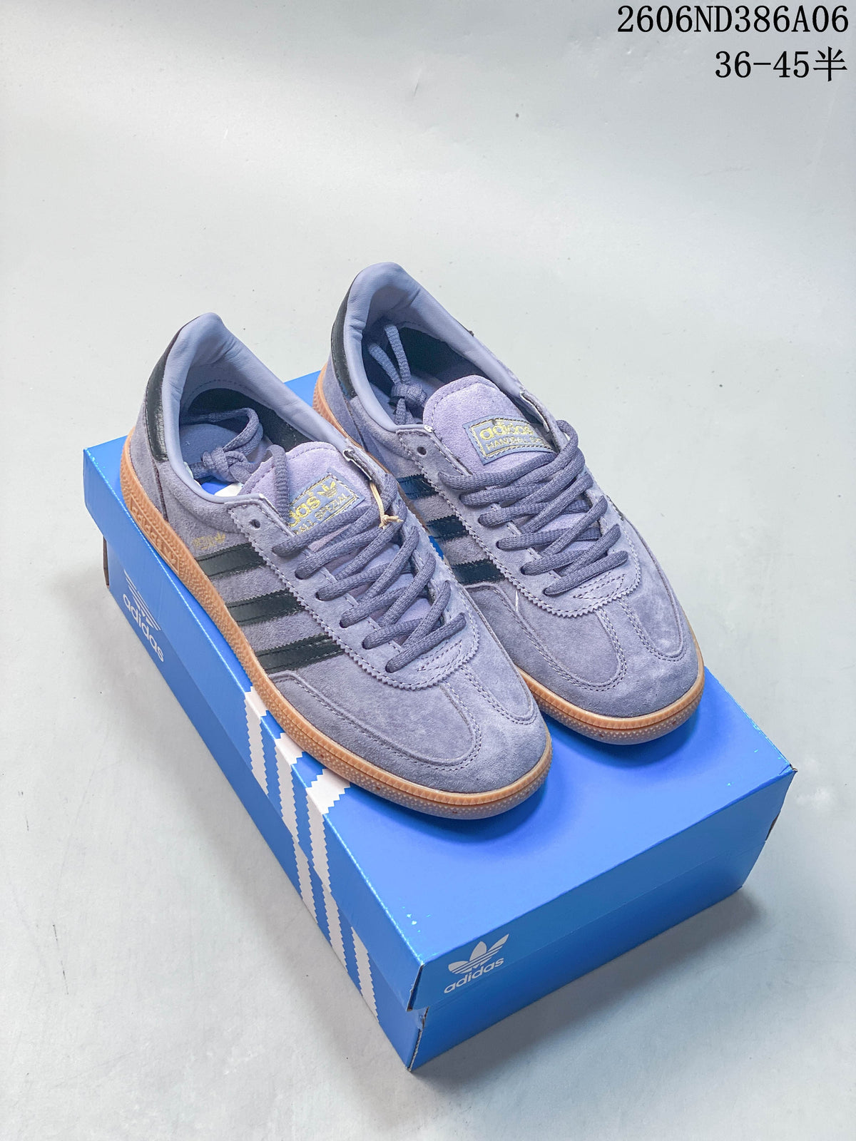 Lavender Adidas Handball Spezial sneakers with dark side stripes and gum outsole, shown on a blue shoebox