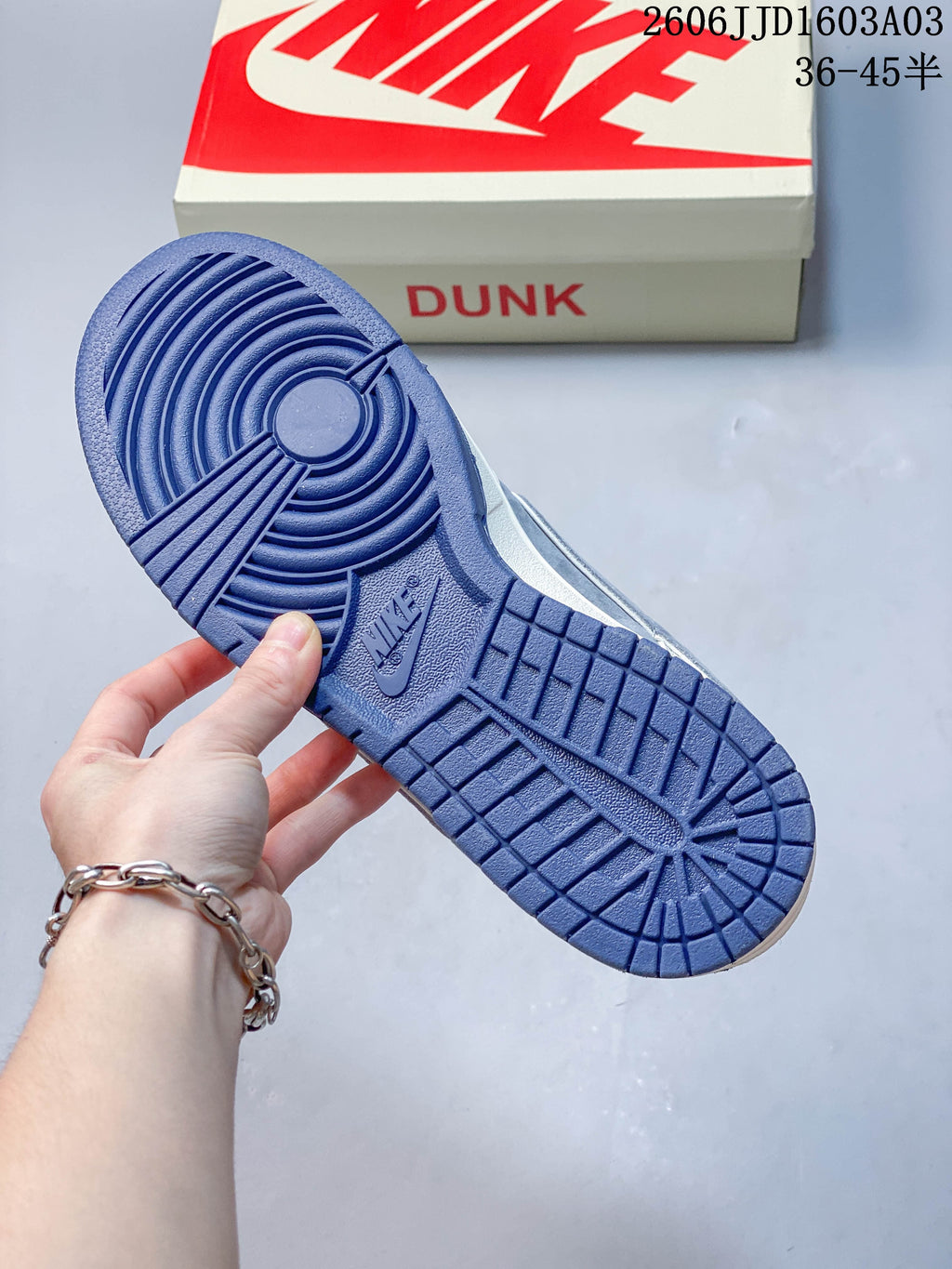 Blue rubber outsole shown from below beside a Nike Dunk shoe box