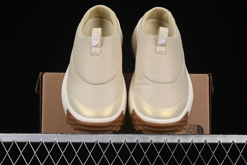 Front view of the pair of mule sneakers resting on the shoebox.