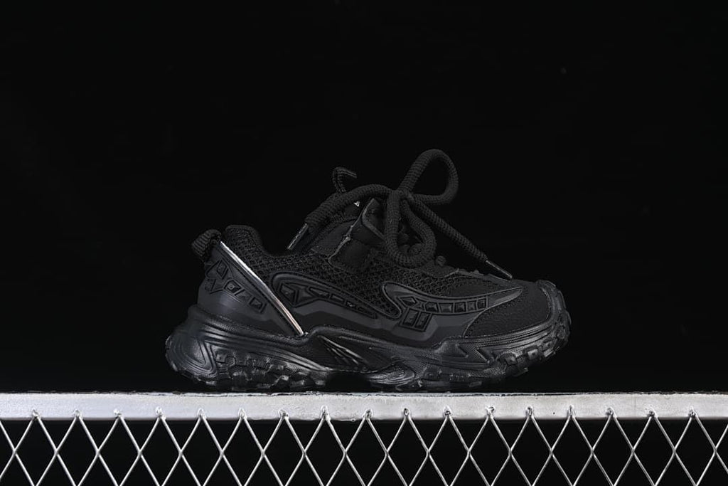 Side profile of a black children's sneaker with a chunky treaded sole.