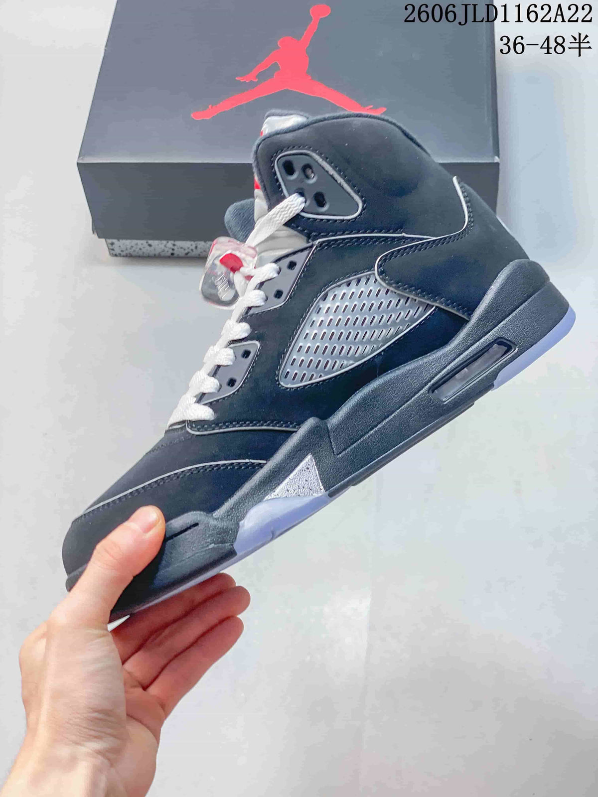 Side view of a dark high-top sneaker with a silver-toned perforated side panel and translucent outsole.