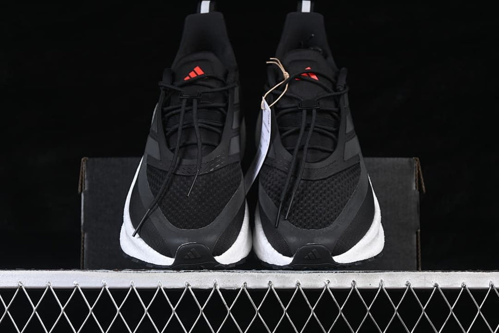 Front view of a pair of black shoes with white midsoles and red tongue logos.