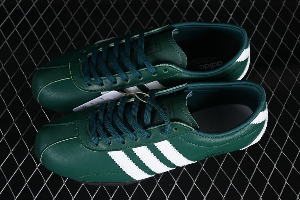 Pair of green low-top sneakers with white stripes and dark laces.