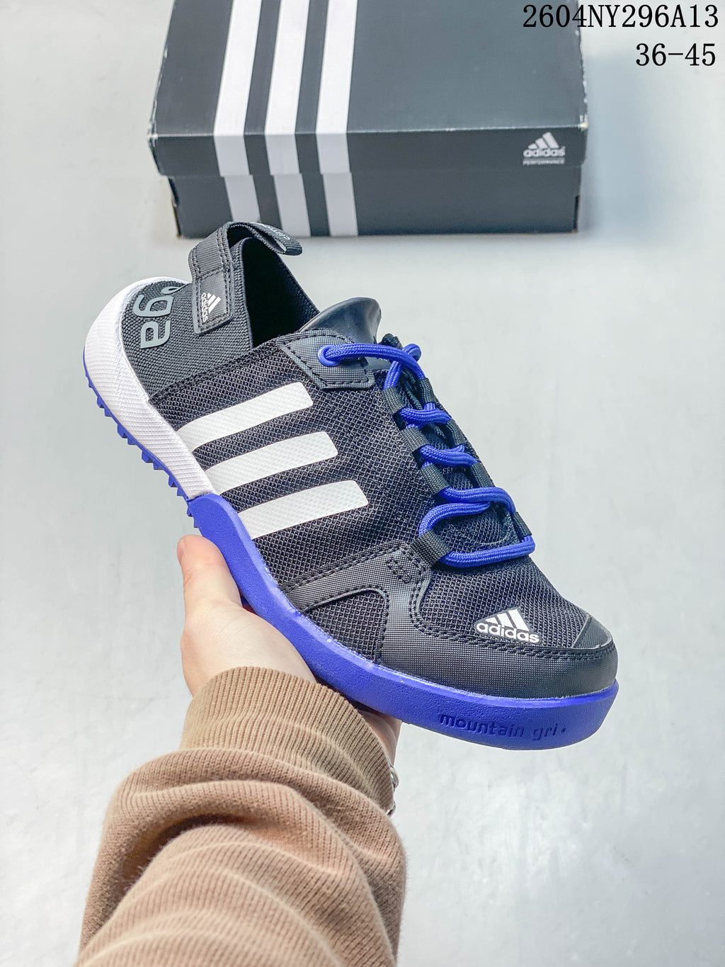 Close-up of a dark gray adidas TERREX shoe with blue laces and blue outsole accents.
