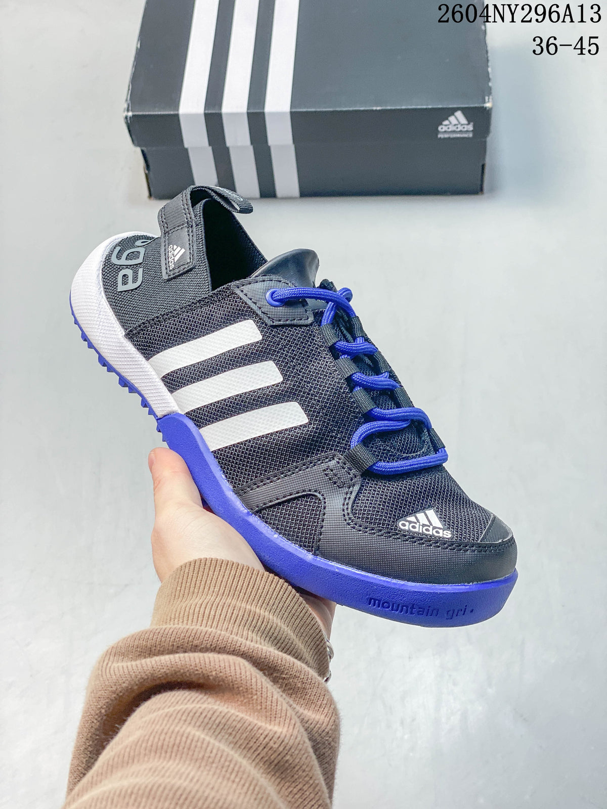 Close-up of a dark gray adidas TERREX shoe with blue laces and blue outsole accents.