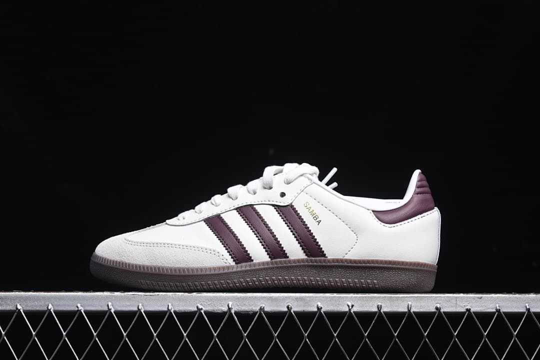 Side view of white adidas Samba OG EMMI sneakers with burgundy stripes and dark outsole