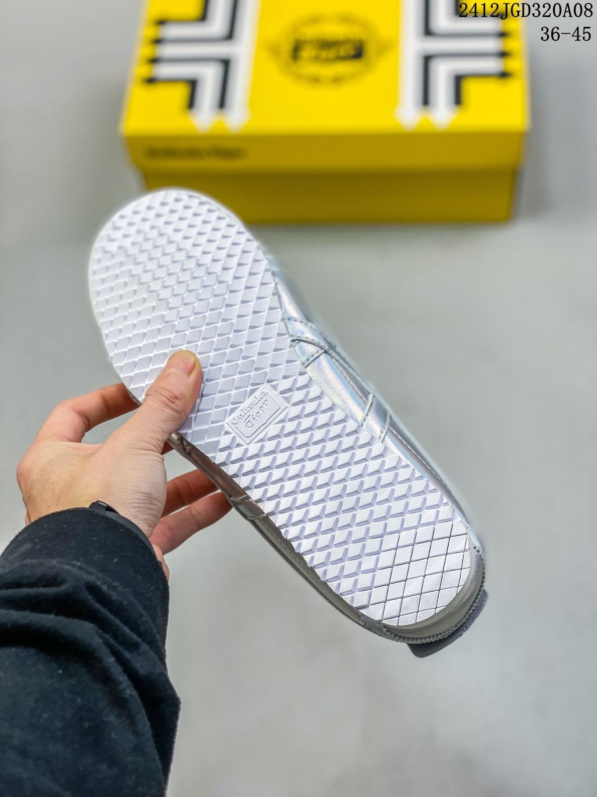Close-up of the white patterned outsole on an iridescent silver sneaker