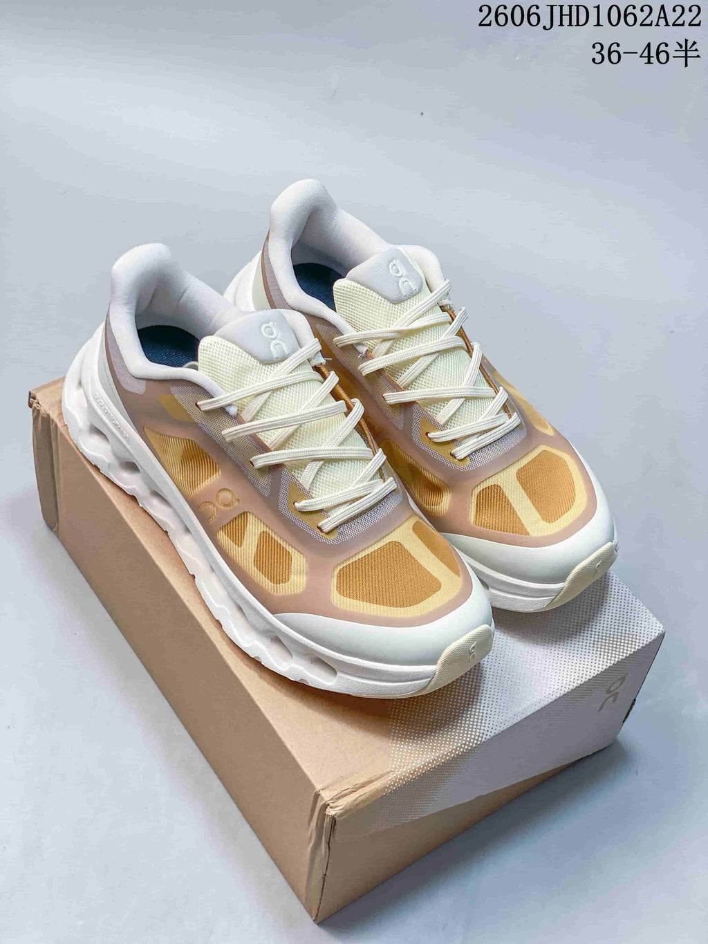 Pair of beige, gold, and white On Cloudtilt Remix sneakers displayed on a shoebox.