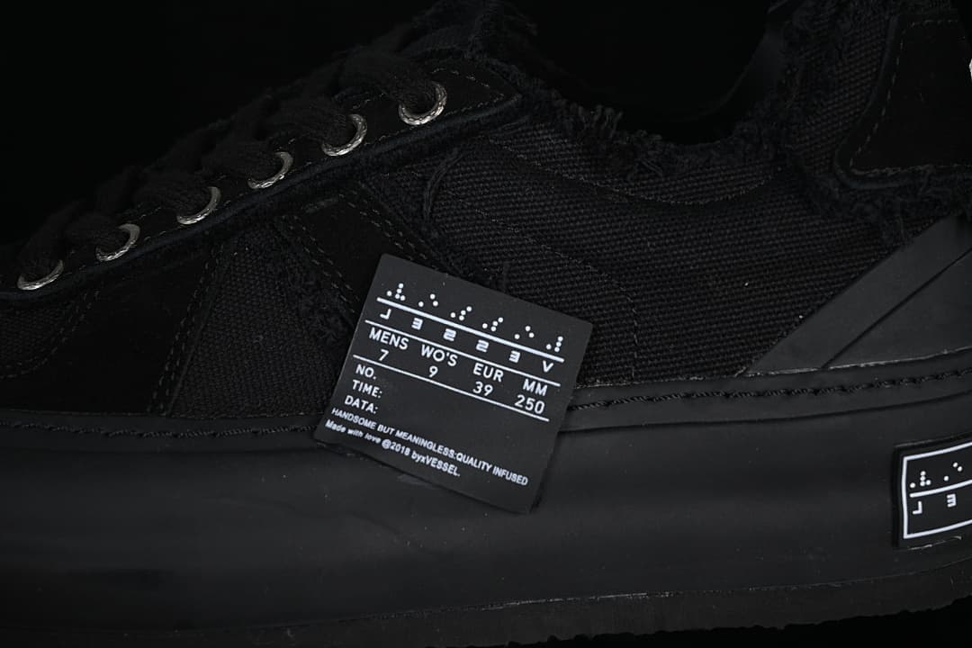 Close-up of black sneaker upper, metal eyelets, and size label
