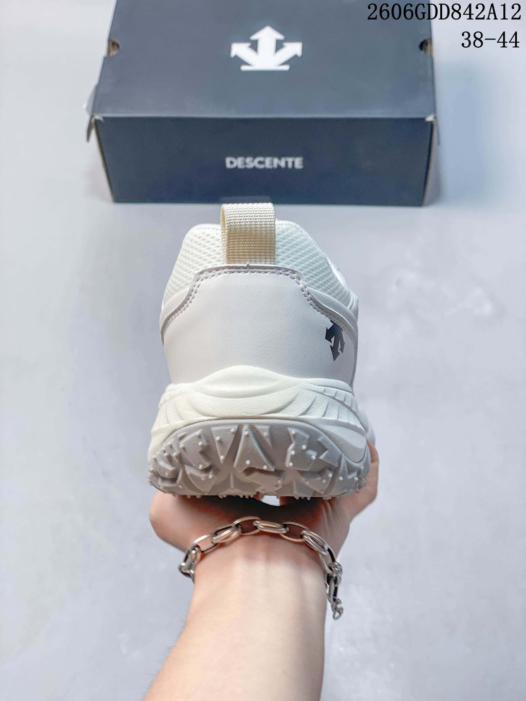 Rear view of the white DESCENTE sneaker showing its heel and textured outsole; the image displays size range 38–44.