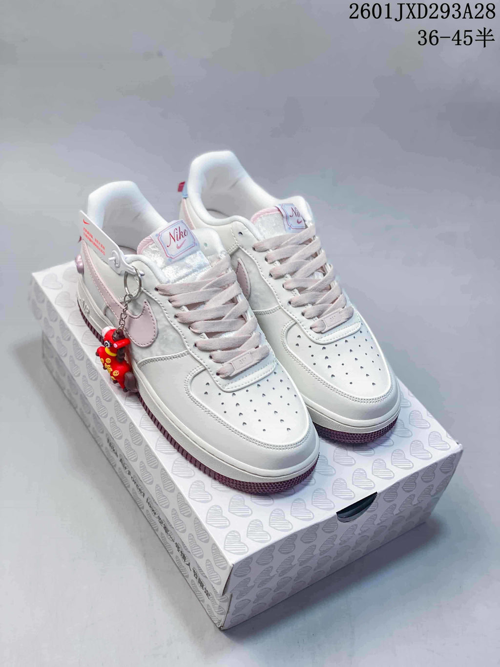 Pair of white and pale pink low-top sneakers with a dangling charm