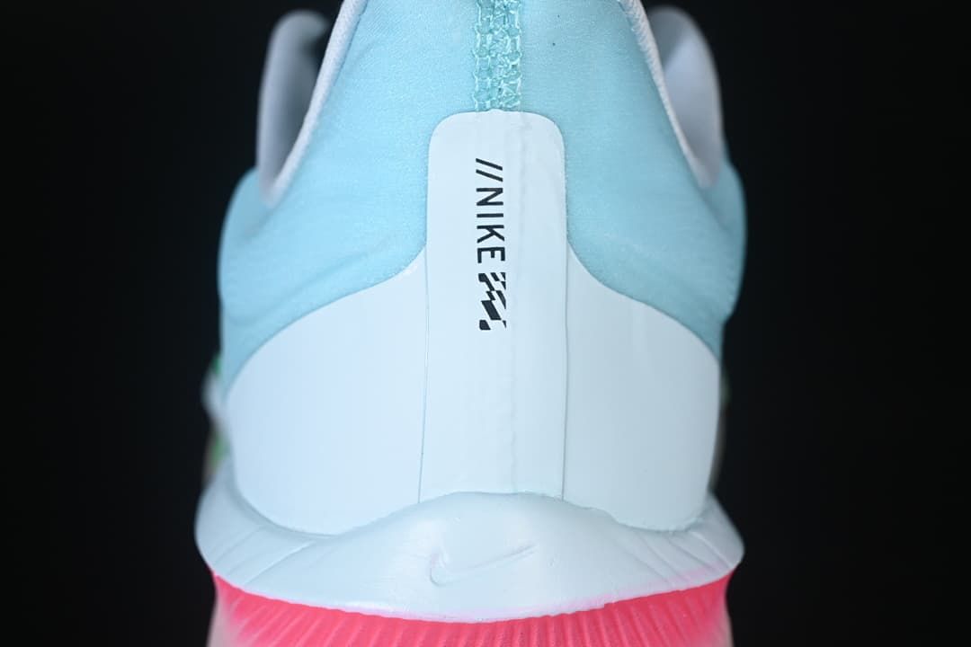 Rear view of the shoe showing the pale blue heel, white panel, and pink midsole accent.