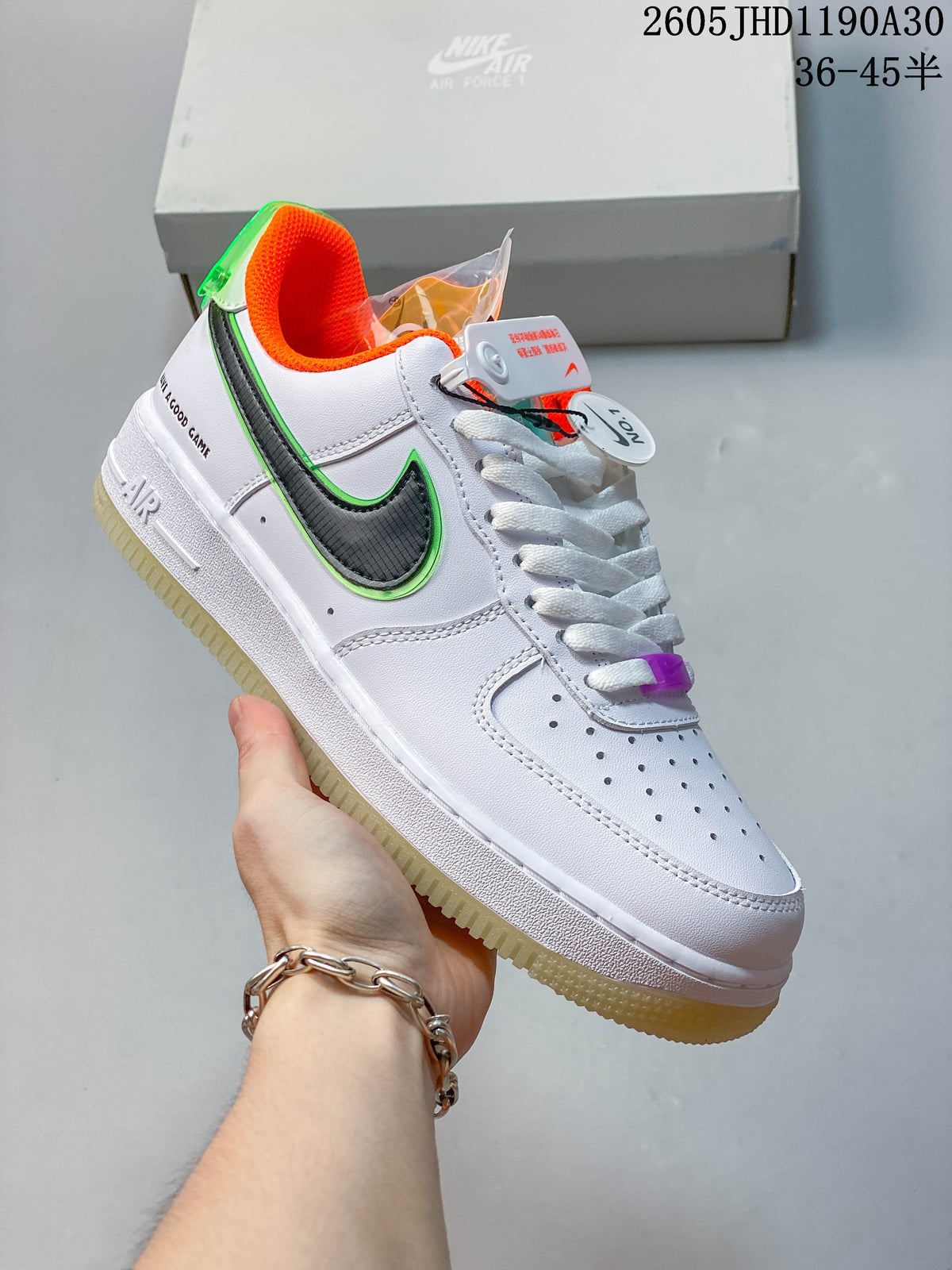 Angled view of the white sneaker with dark patterned side panel, green trim, orange lining, and translucent outsole