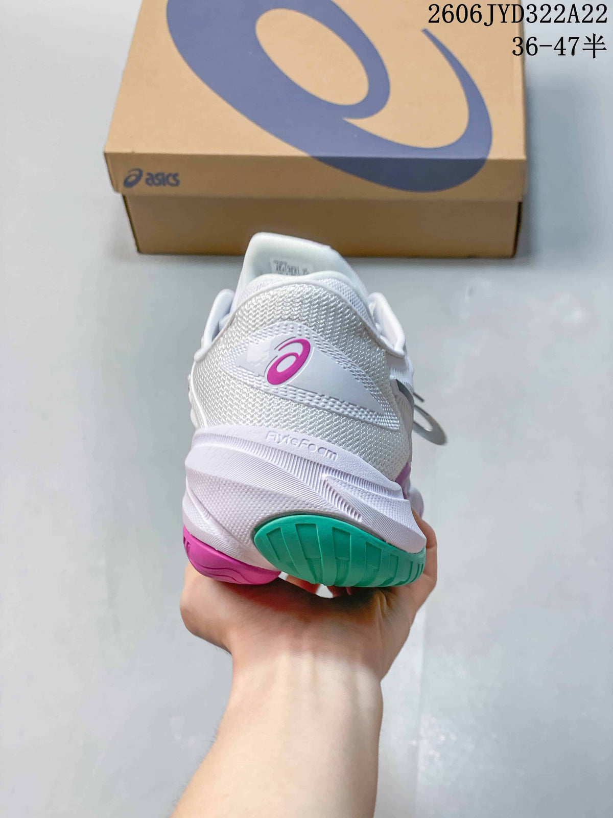 Rear view of a white ASICS tennis shoe with a magenta logo accent and teal outsole.