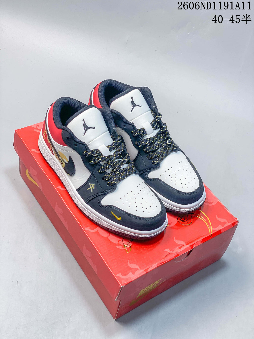 Pair of low-top sneakers with white, navy, red, and gold-toned details on a red box