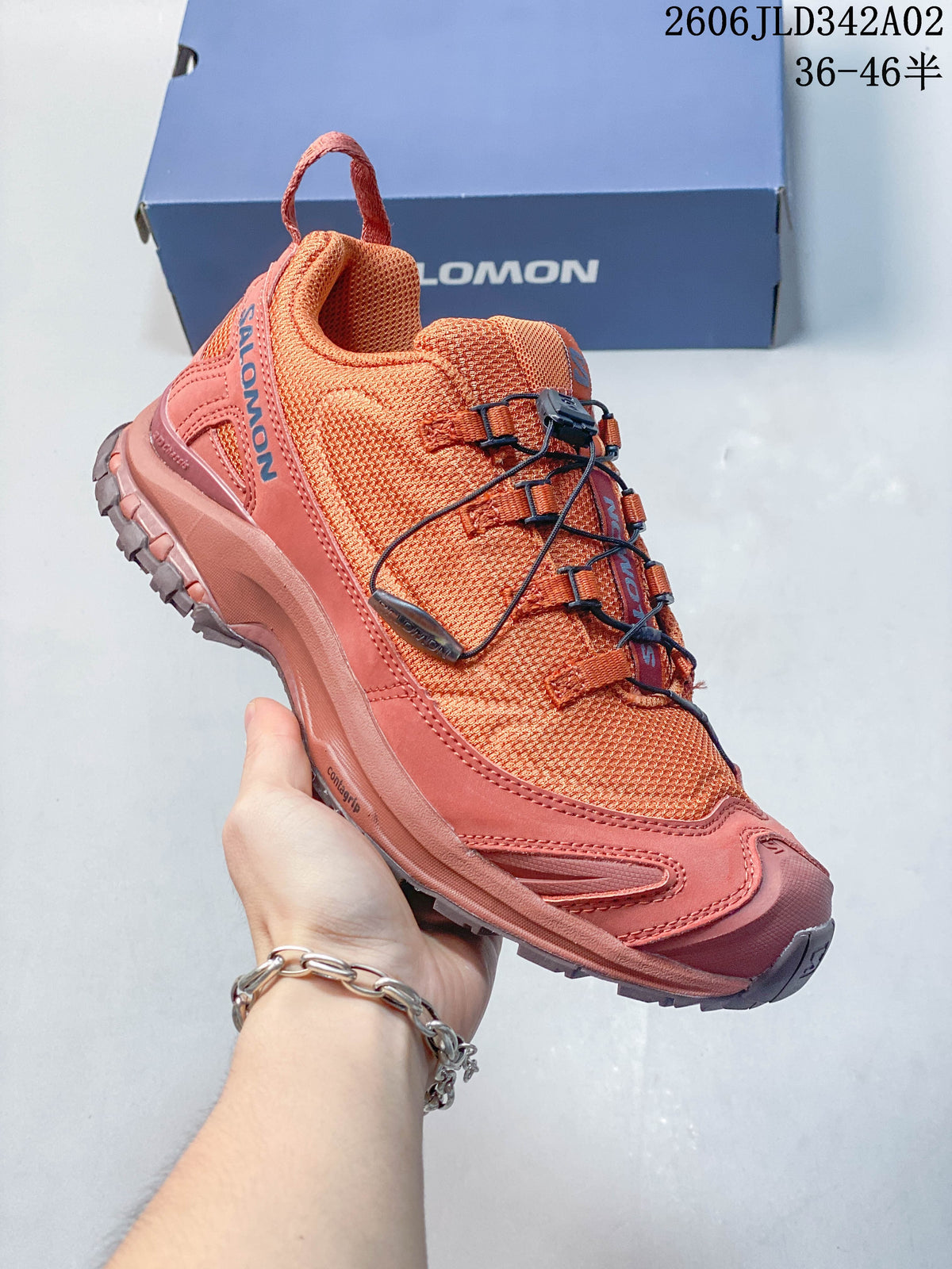 Angled side view of the coral Salomon trail shoe.