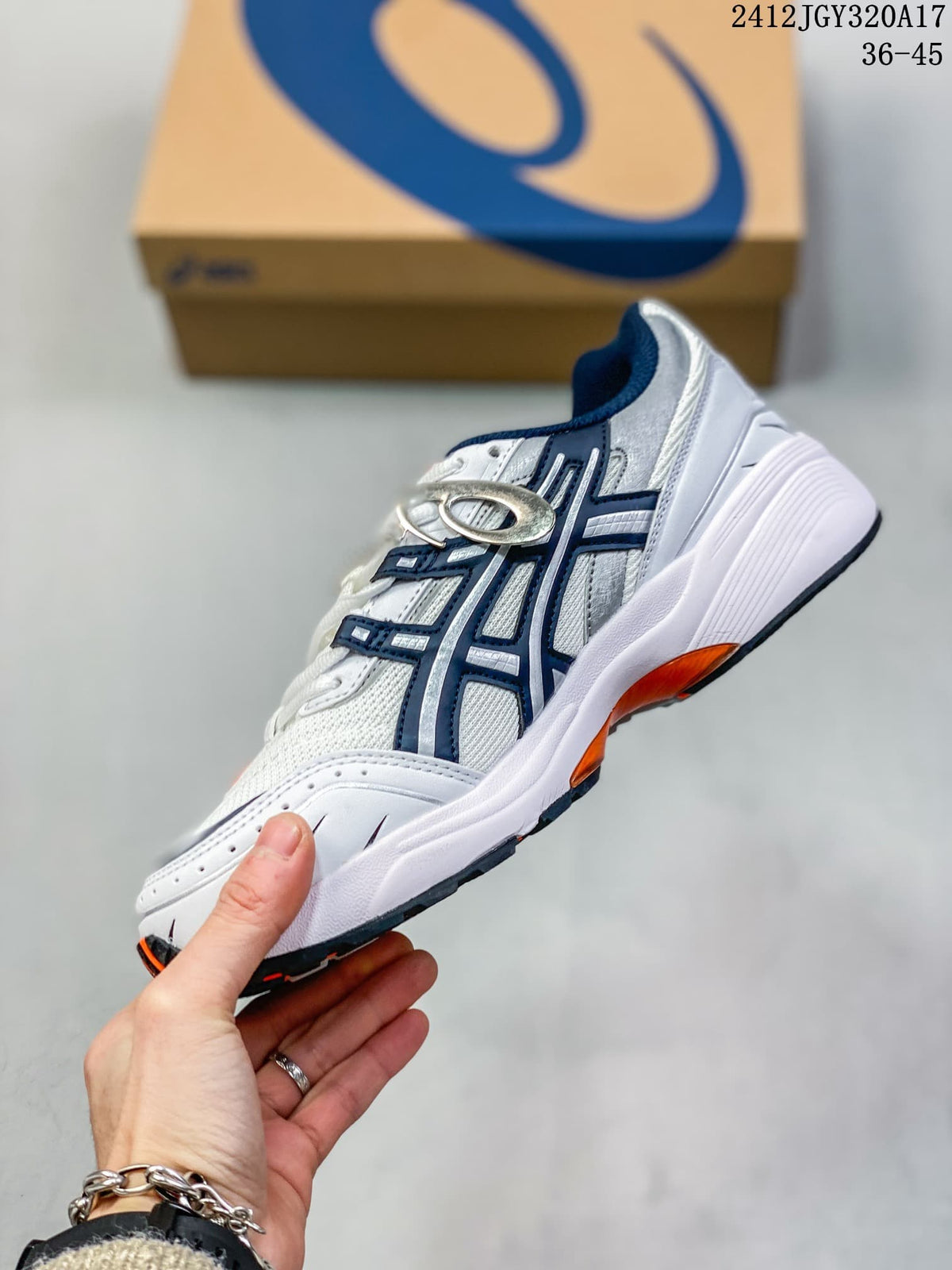 Side profile of the white ASICS GEL-1090 sneaker with navy overlays and orange sole accents