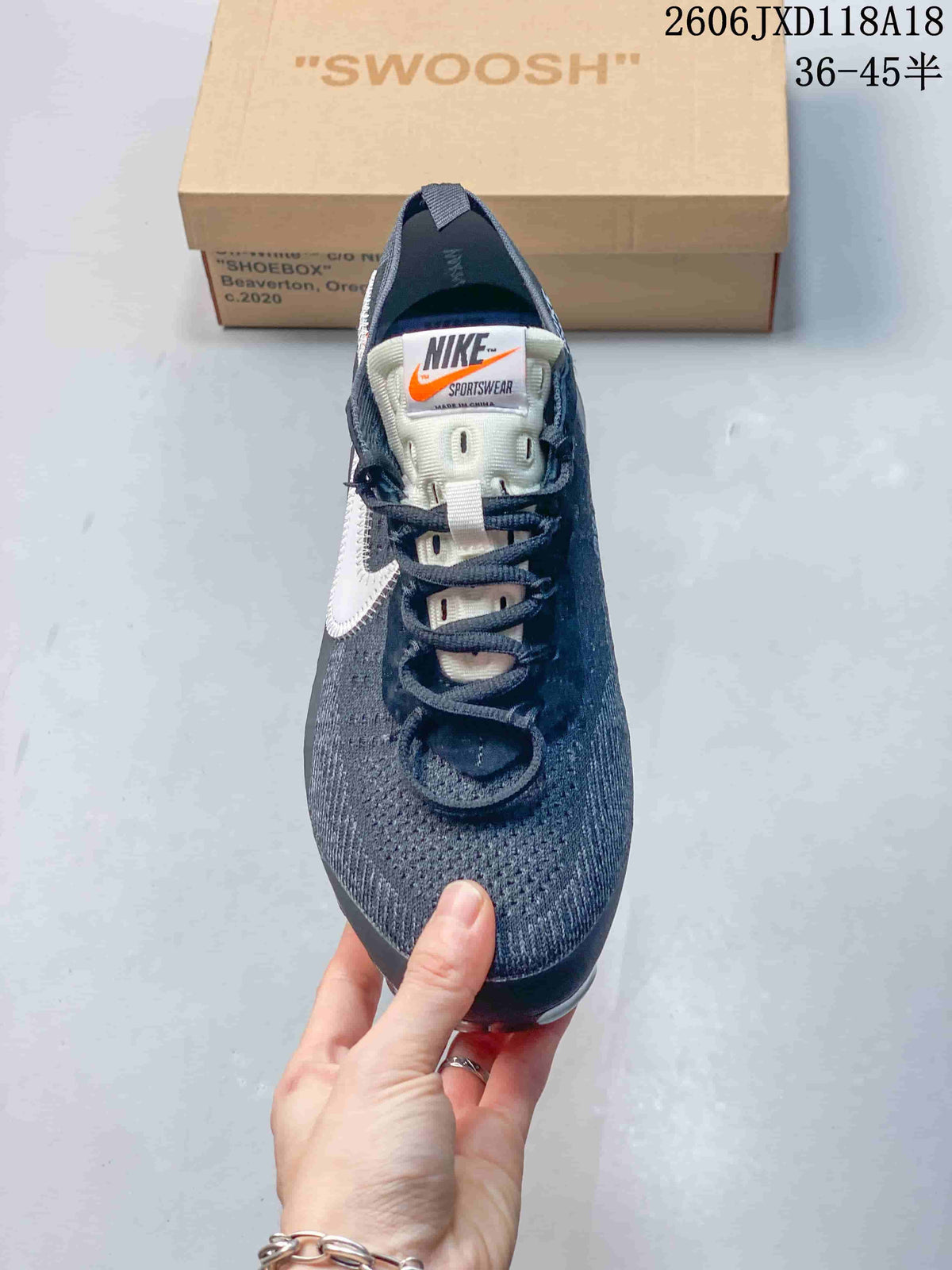 Front view of a gray Nike sneaker with dark laces, a white tongue label, and orange accent.