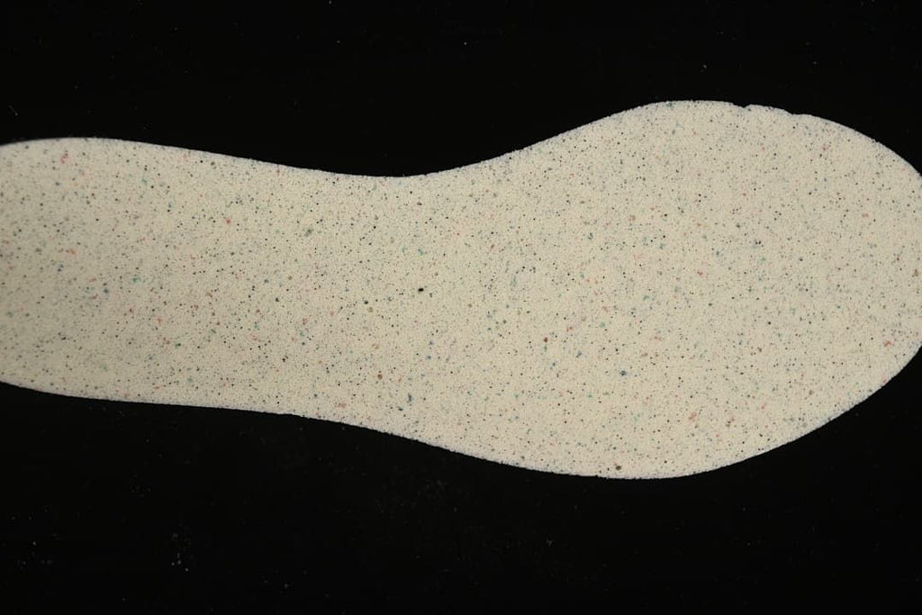 Light-colored shoe insole shown from the underside, with small multicolored speckles.