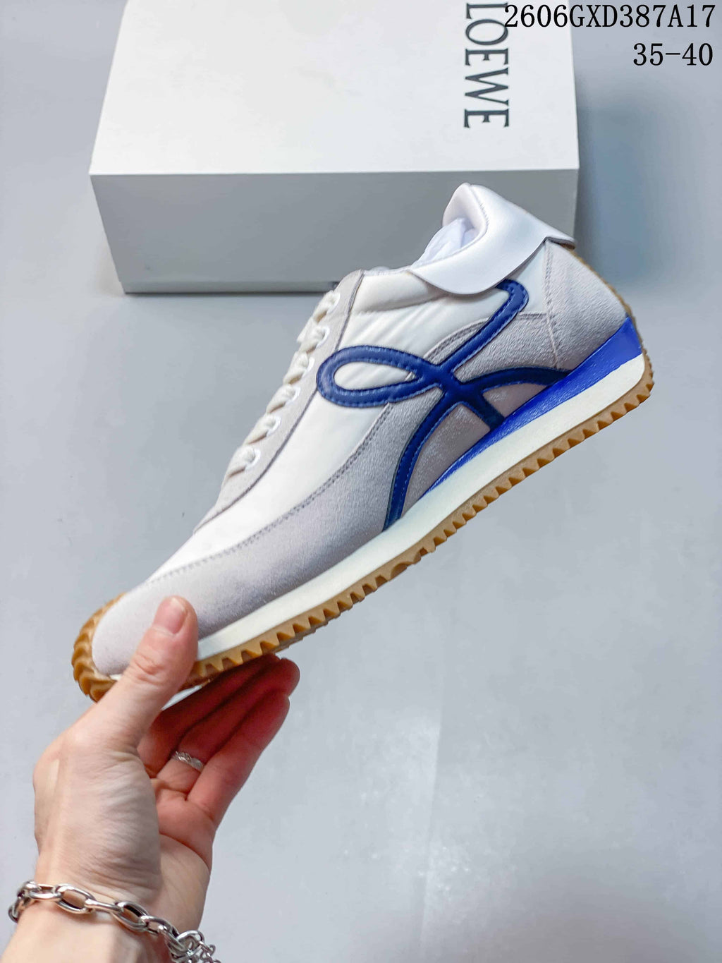 Side view of a white and pale gray sneaker with blue detailing