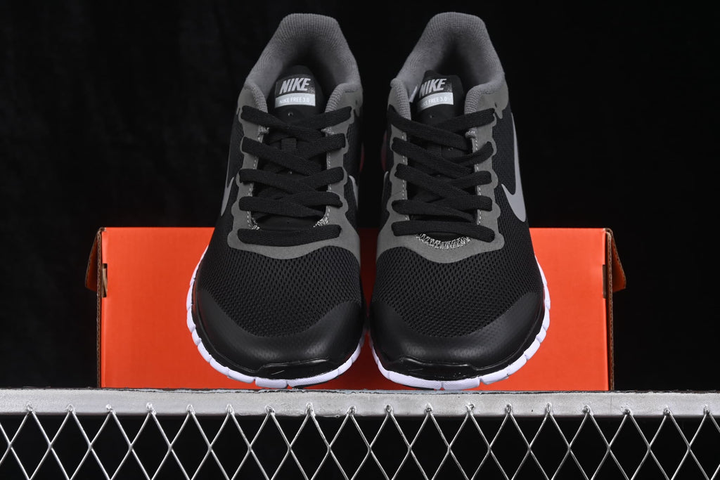 Front view of the pair positioned over the orange shoe box, showing the black mesh toes and white outsoles.