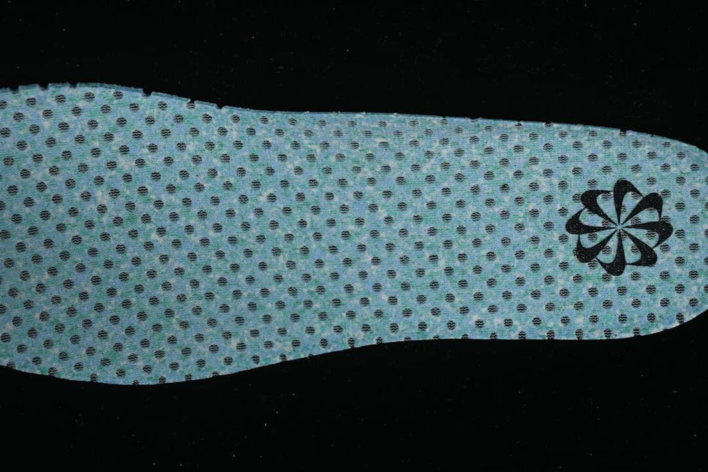 Reverse side of a perforated blue insole with a small dark emblem.
