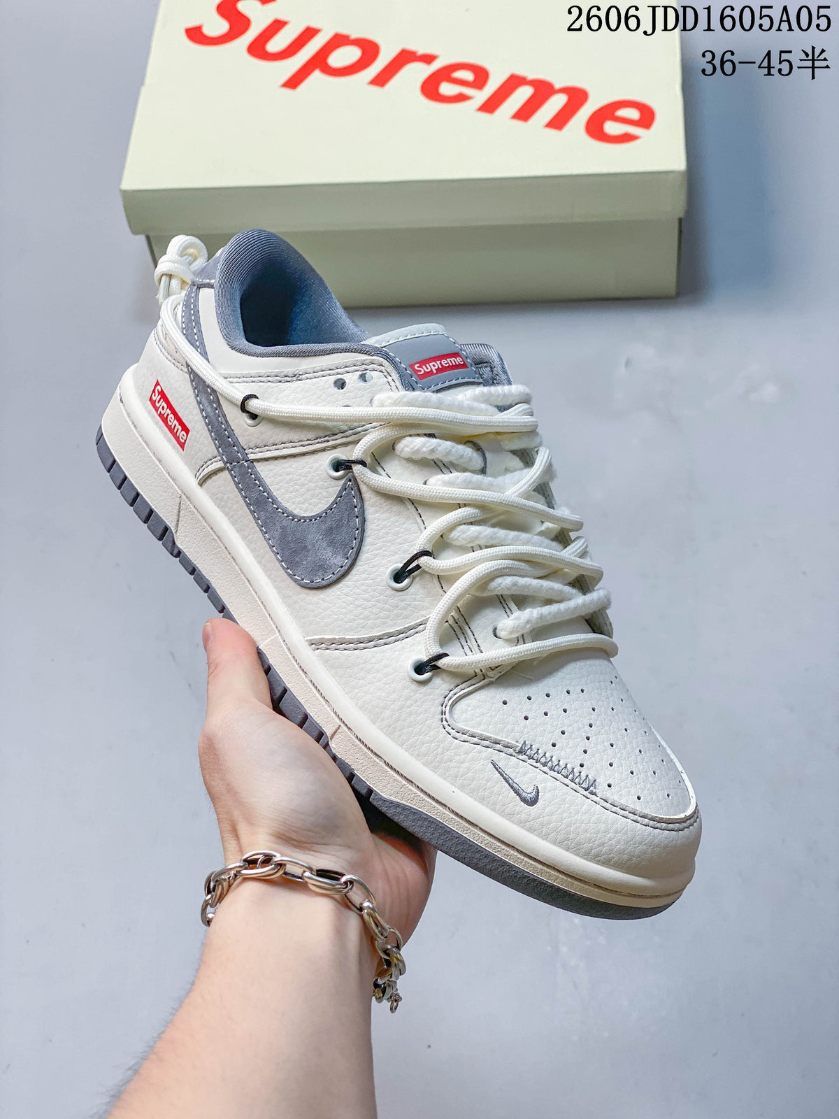 Off-white low-top sneaker with gray accents, rope-style laces and a branded box in the background.