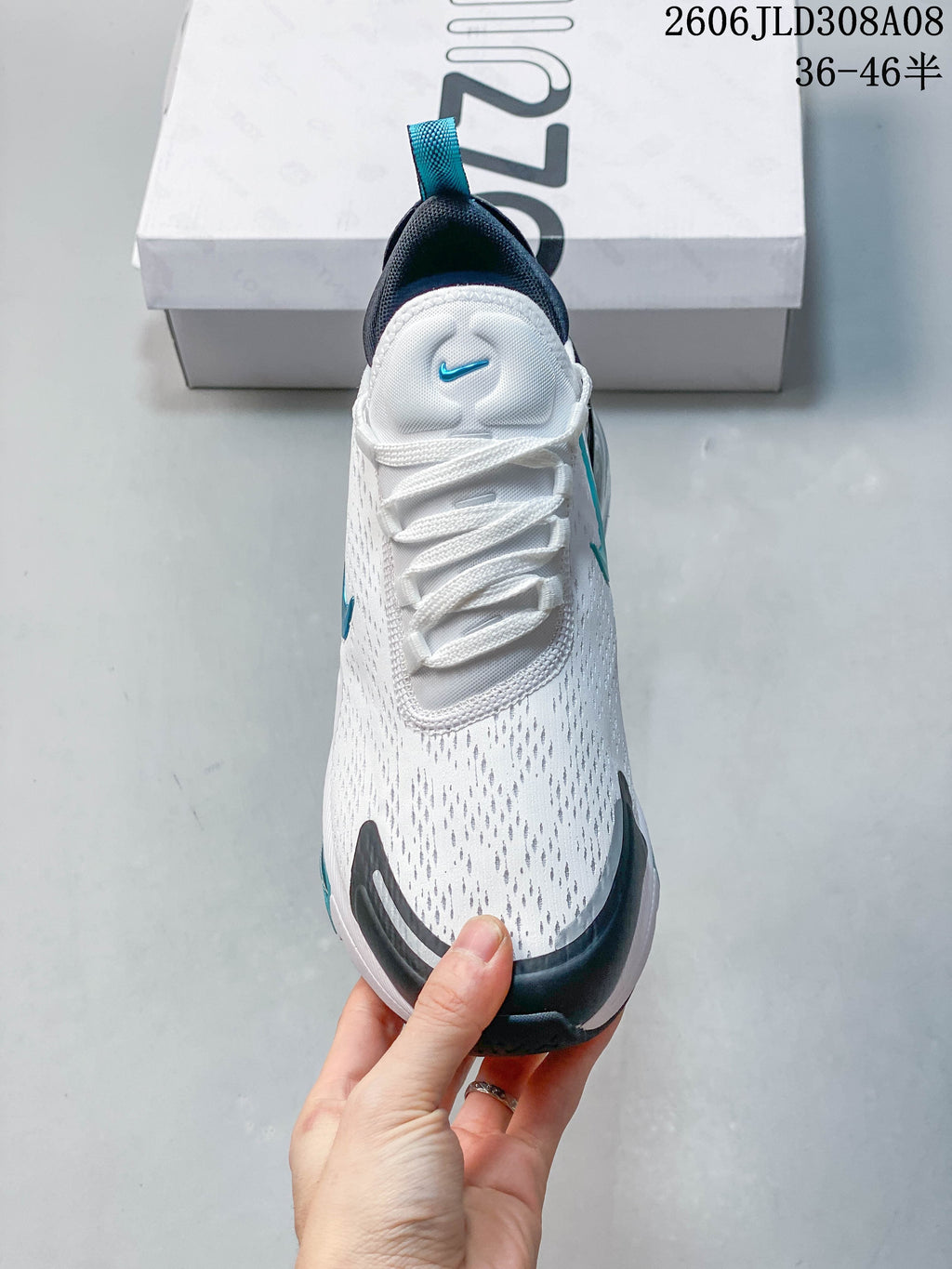 Front view of a white Nike Air Max 270 sneaker with dark toe trim and turquoise details