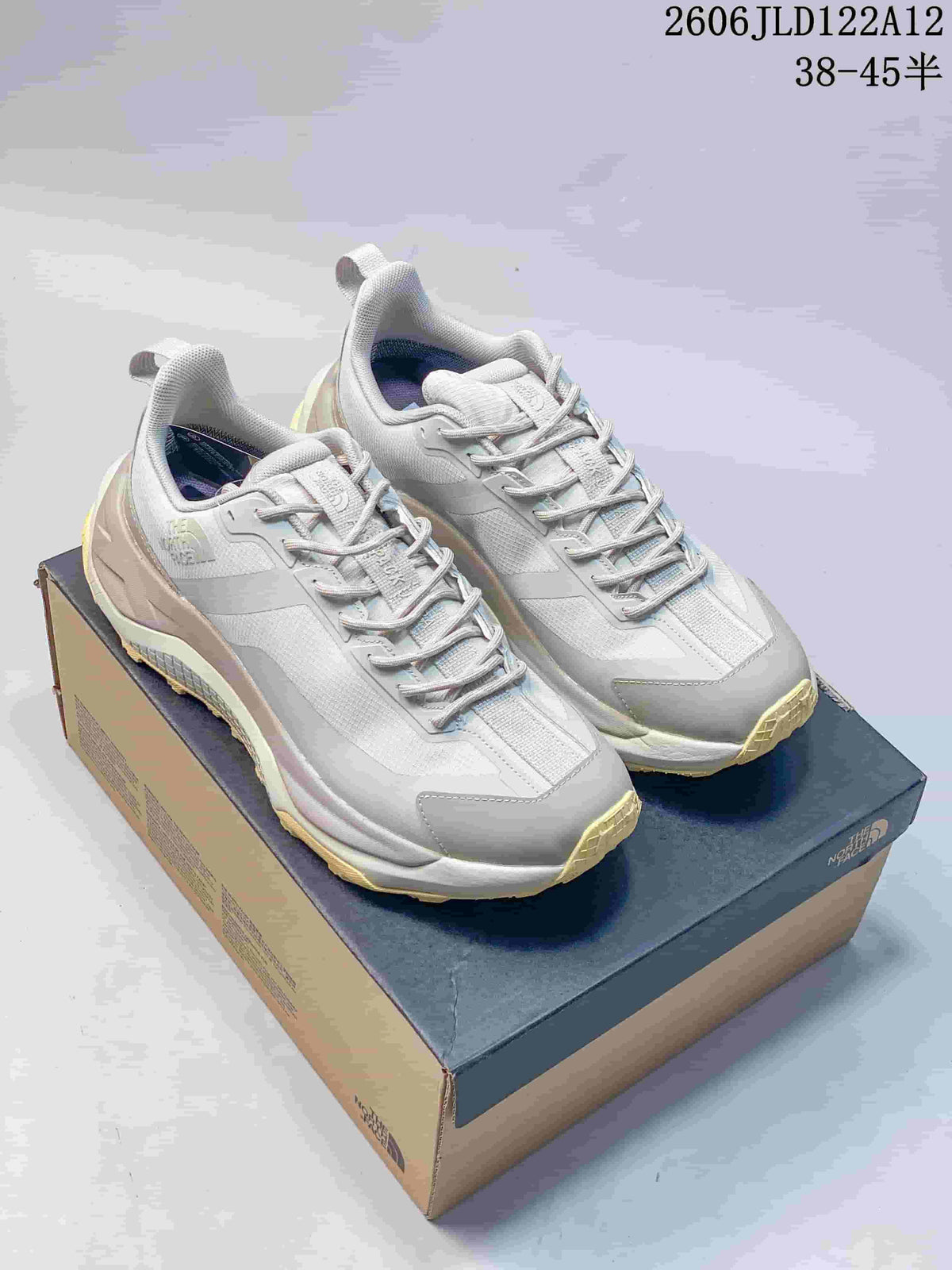 Pair of light gray The North Face Fastpack low-cut hiking shoes with pale yellow outsoles, displayed on a shoe box.